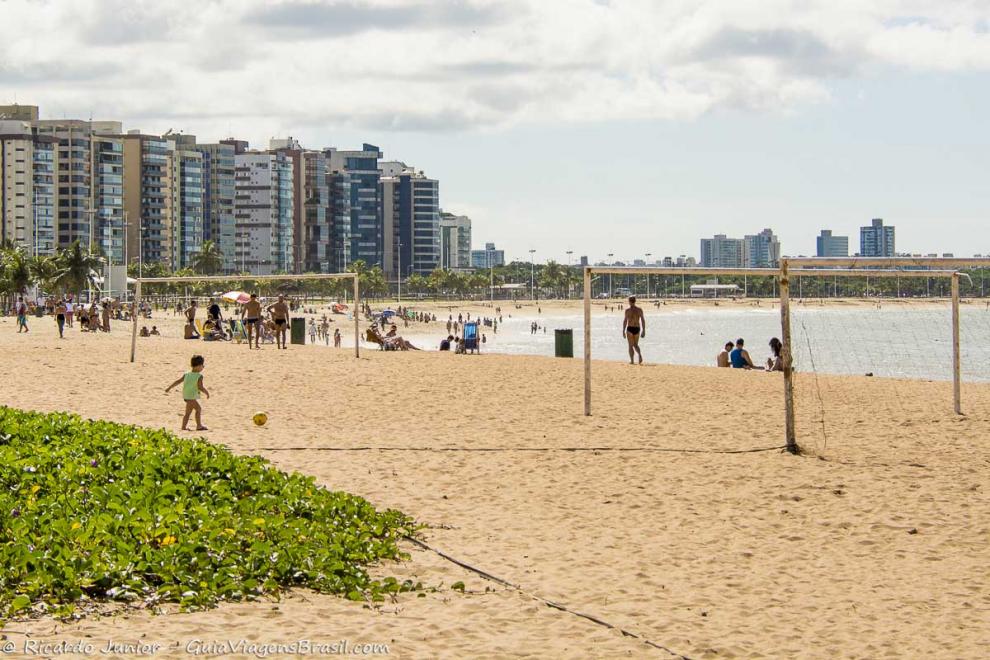 Imagem de uma criança jogando bola com o pai na Praia de Cambori.